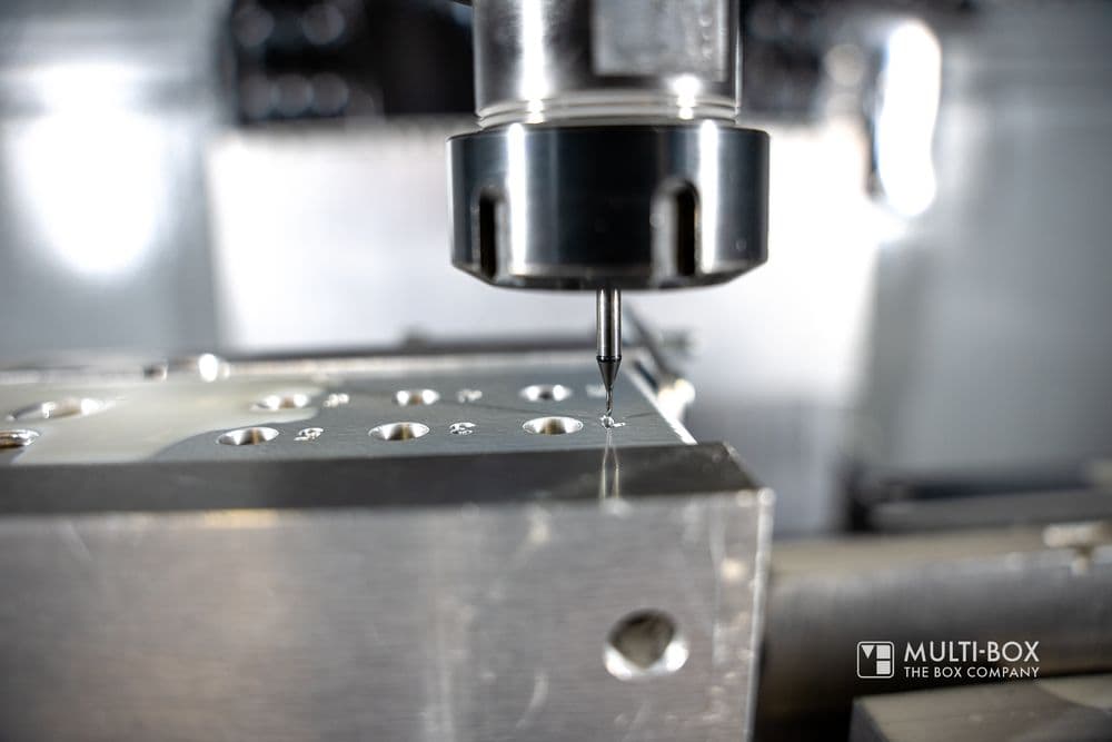 Close-up of a CNC tool drilling precise holes into a metal piece.