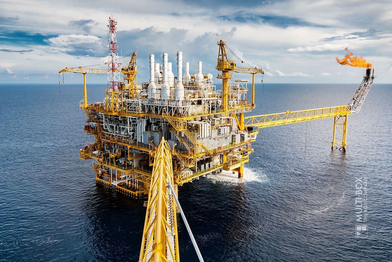 An offshore oil platform in the open sea with a gas flame and industrial facilities.