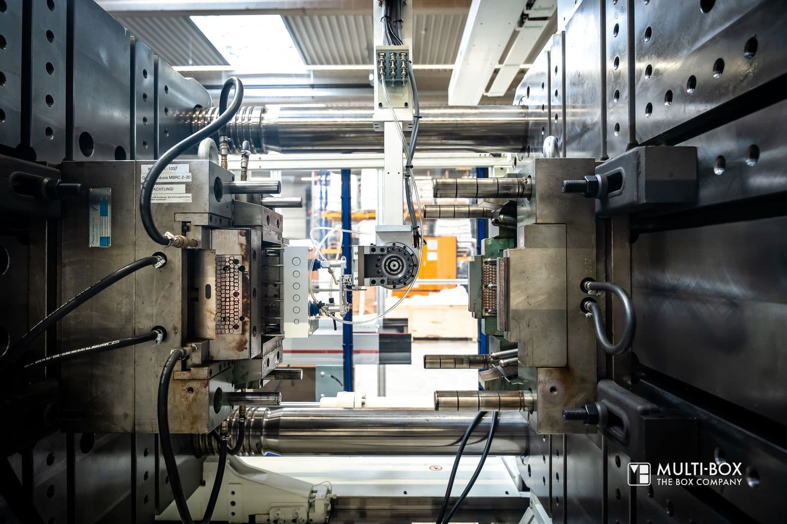 Geöffnete Spritzgussmaschine in der Produktion von MULTI-BOX, die ein fertig geformtes Kunststoffgehäuse entnimmt.